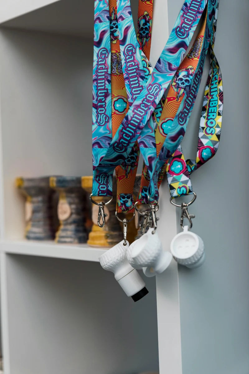 Colorful lanyards with keys and small containers on a white shelf.