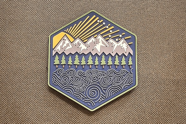 Hexagonal badge with mountain and tree design on a textured brown background